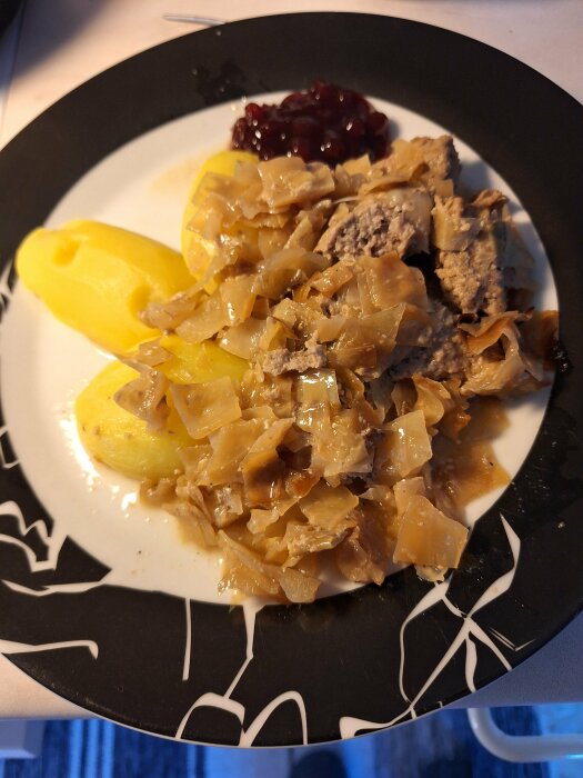 En tallrik med kålpudding, potatis och lingonsylt serverad som middag.