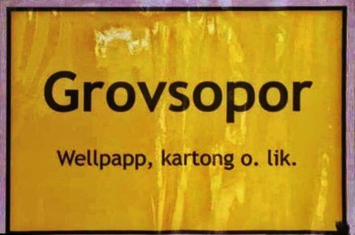 Skylt med texten "Grov­sopor" och "Wellpapp, kartong o. lik." på gul bakgrund.