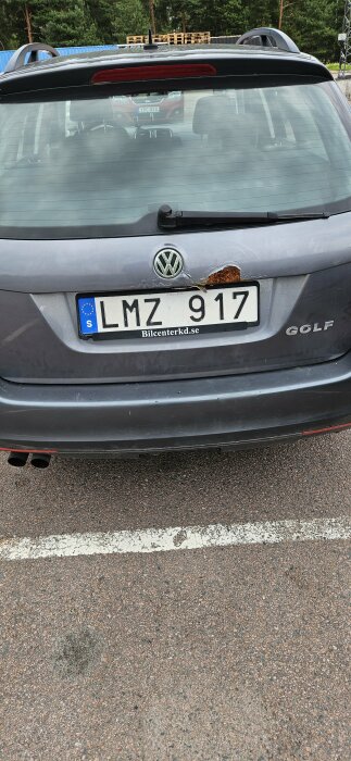 Rostig baklucka på en Volkswagen Golf med registreringsskylt LMZ 917 parkerad utomhus.