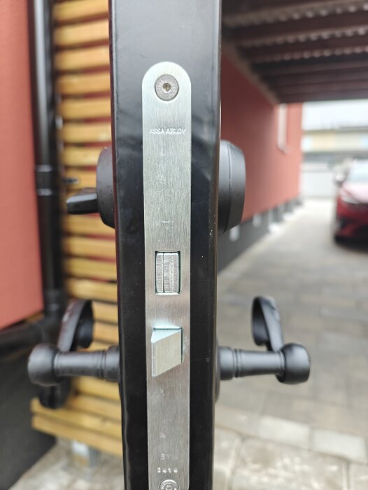 Bild av en närbild på en installerad dörr med ASSA ABLOY låssystem, med fokus på låsets mekanism och omgivningens ytterdörrmiljö.