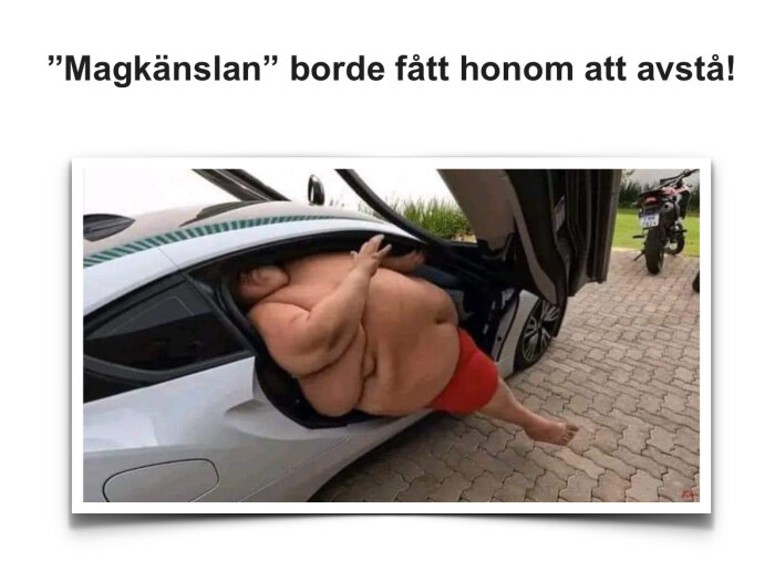 En person försöker ta sig ur en sportbil med uppfällt dörr, med motorcykel i bakgrunden.