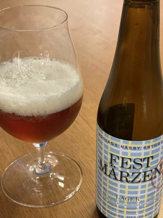 Ölglas med skummande bärnstensfärgad lager och flaska med etikett "Fest Märzen".