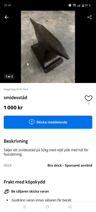 Ett smidesstäd av metall på ett cementgolv. Det har en spetsig ände och en platt bas med hål för fastsättning.