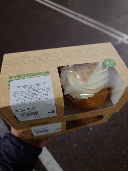 Förpackning med två nygräddade semlor från Coop, inklusive saffran och mandel, syns genom plastfönster.