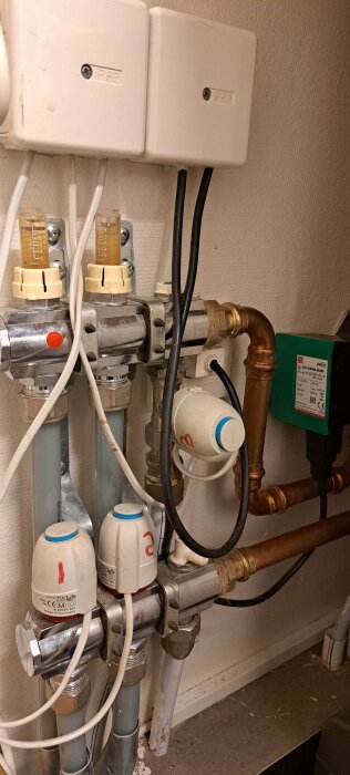 Vattenburen golvvärmeinstallation med ventiler och rörledningar, varav några är numrerade.