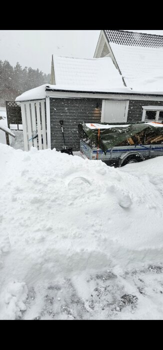 Snötäckt byggnad med stora fönster och ett släp lastat med ved, fotograferat i vinterväder.