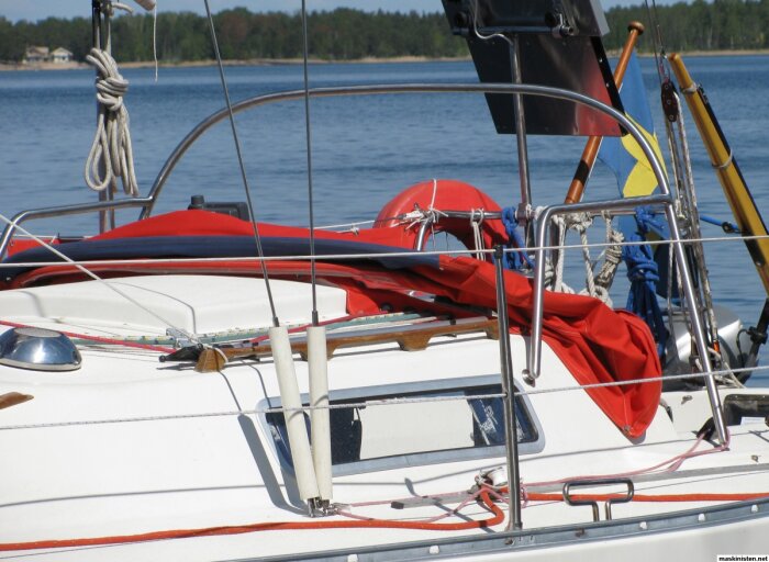 Grabbräcke på segelbåt med rött kapell i bakgrunden, används för att hålla balansen när det blåser.