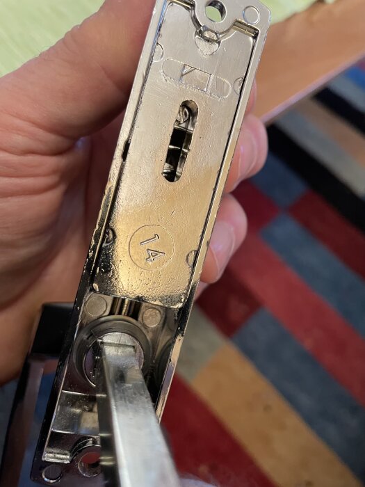 Närbild på ett handtag med lås från ASSA Abloy 844-S, där metallplattan tas bort för inspektion.