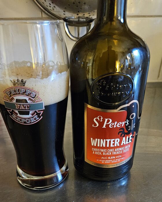 Flaska och glas med St Peter's Winter Ale, en mörk öl med etikettens text "Christmas cake aromas with a rich, black treacle taste".