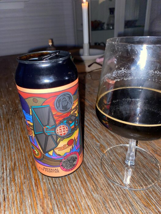 Burk och glas med Imperial Pie Fighter öl från Amundsen på ett bord, stearinljus i bakgrunden.
