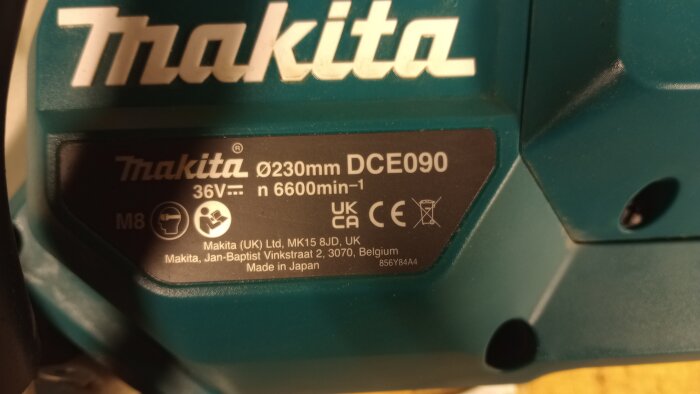 Närbild av Makita kapmaskin, modell DCE090, med specifikationer inklusive skivdiameter 230 mm, 36V och varvtal 6600 min⁻¹.