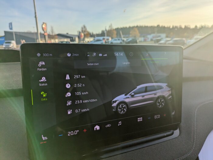 Bilens display visar körstatistik: 297 km, 2:52 timmar, snittfart 105 km/h, energiförbrukning 23.9 kWh/100 km. Solbelyst skärm i en parkerad bil.
