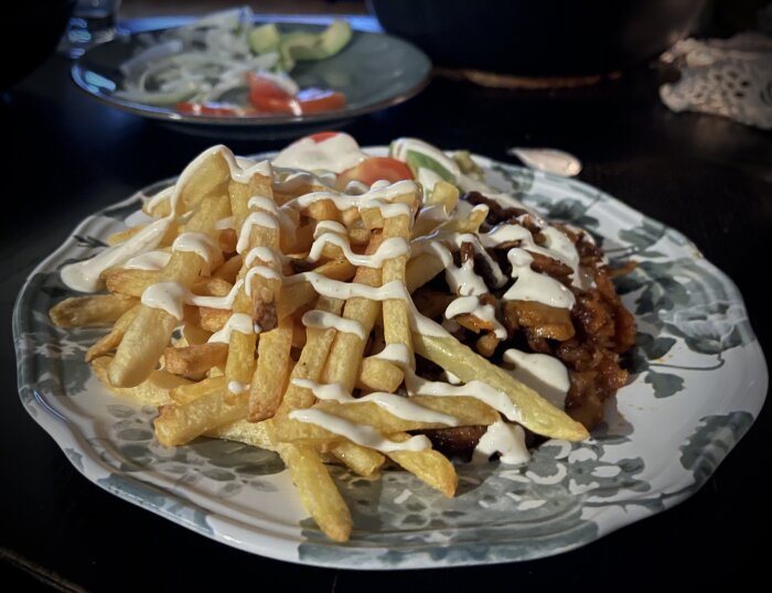 Pommes frites och kycklingkebab med vitlökssås på en tallrik med sallad i bakgrunden.