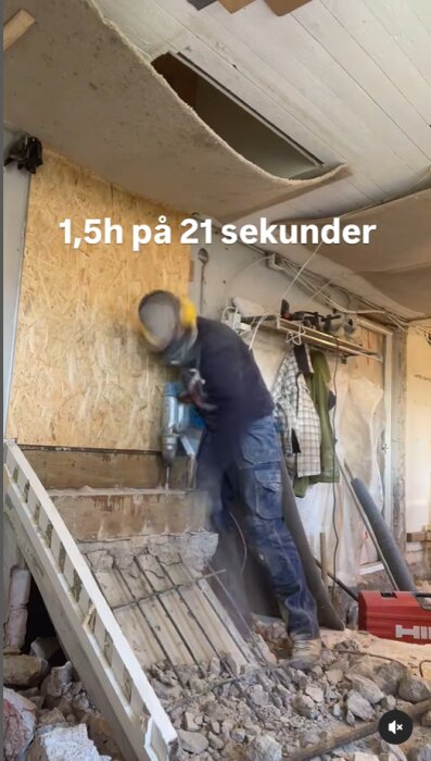 Person med skyddsutrustning bilhugger betongtrappa inomhus med en Hilti-maskin, omgiven av byggmaterial och verktyg.