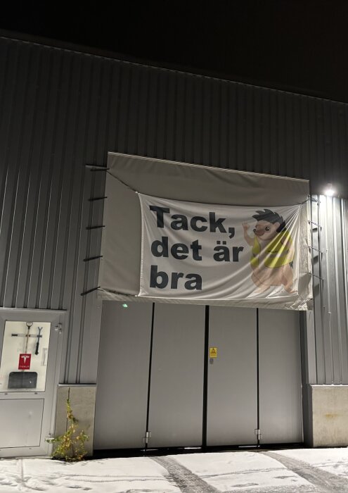 Banner med texten "Tack, det är bra" och en tecknad figur vid Teslas servicenter.