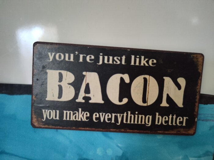 Träskylt med texten "you're just like bacon you make everything better" mot en blå bakgrund.