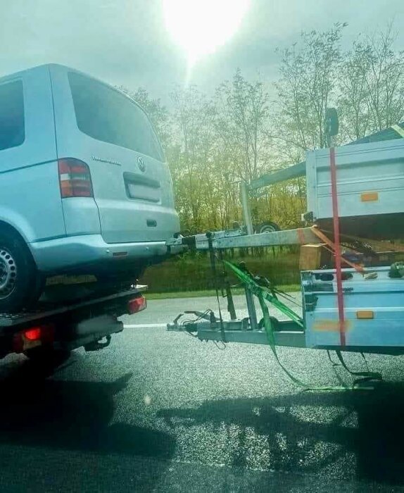 Bil transporterad med släpvagn under solig dag på landsväg.