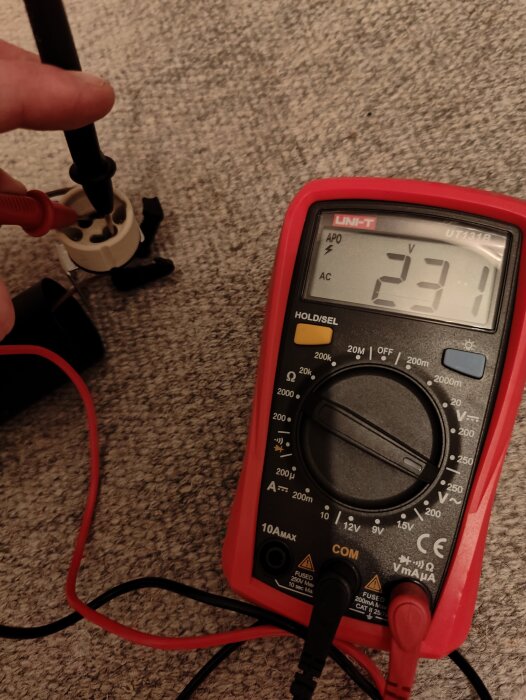 En multimeter mäter 231 volt AC i ett eluttag.