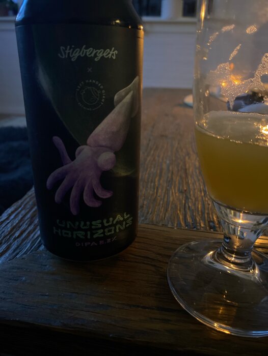 En flaska Stigbergets "Unusual Horizons" DIPA med ett glas öl på ett träbord.