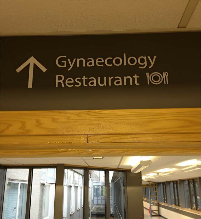 Skylt i en korridor med texten "Gynaecology Restaurant" och pilar uppåt, samt symboler för bestick.