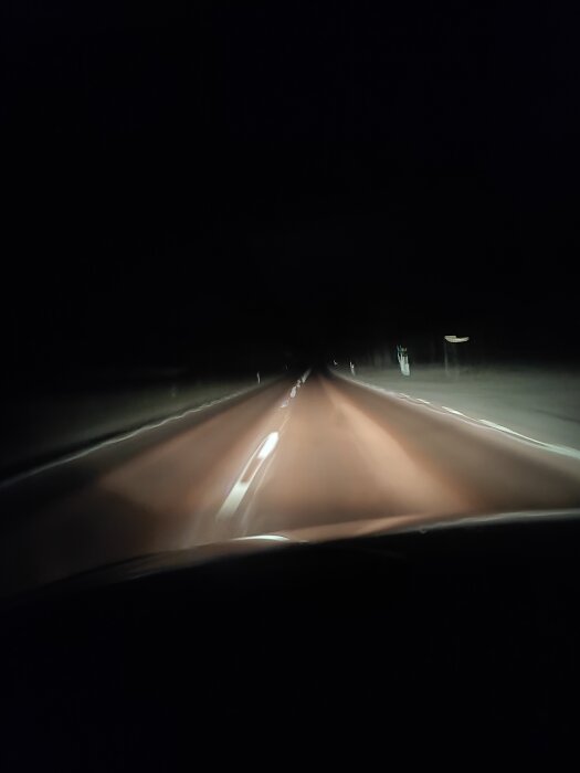 Nattväg sedd från bil med LED-ramp och halvljus aktiverat, visar belysningens effektivitet på mörk landsväg.