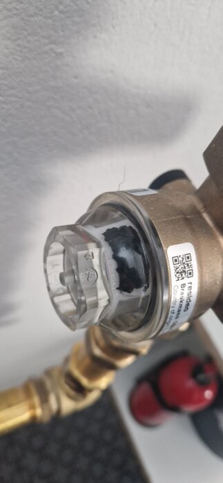Filter med ansamling av svarta plastbitar i en vattentrycksregulator, relaterat till högt vattentryck i samband med kommunal VA-anslutning.