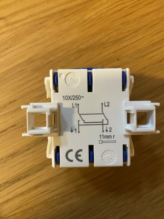 Strömbrytare med kopplingssymboler och CE-märkning på en träyta.