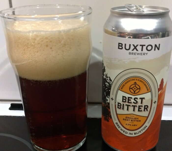 Burk och glas med Buxton Brewery Best Bitter öl, mörk vätska med skum på glaset.