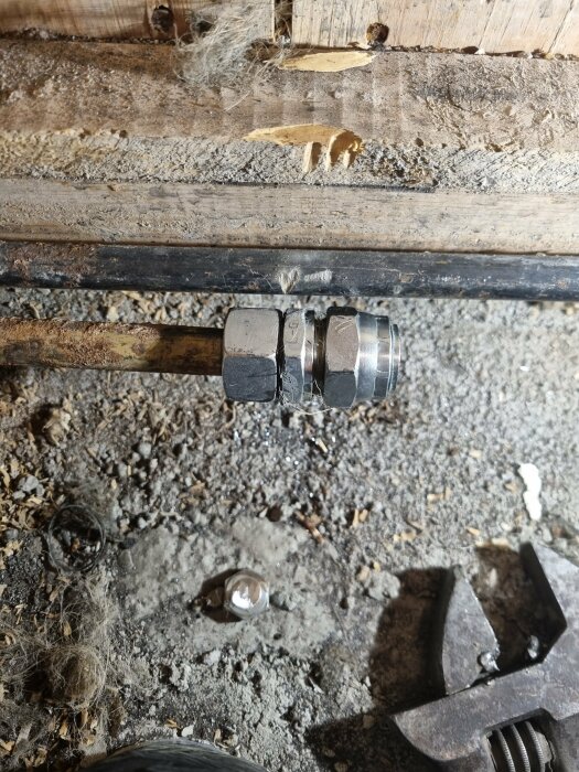 Rörkoppling och elementinstallation i grov träyta samt verktyg och damm.