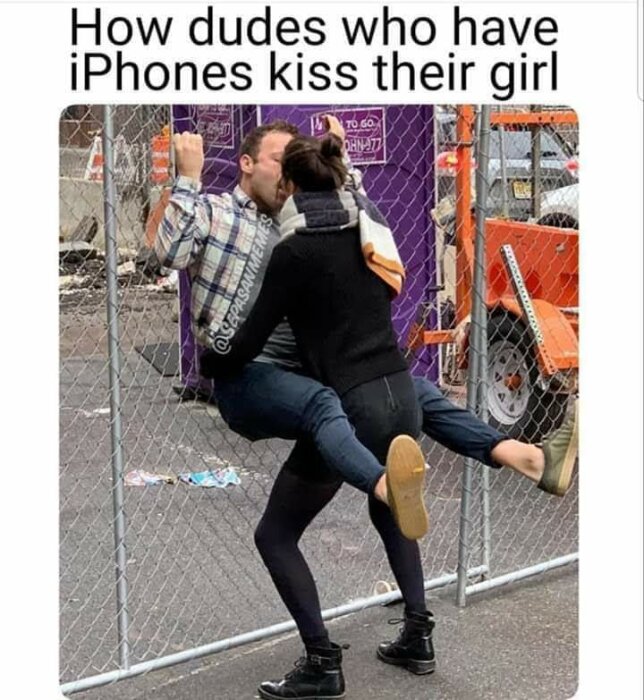 Par som kysser varandra genom ett stängsel, mannen lyfter kvinnan. Text ovan: "How dudes who have iPhones kiss their girl.