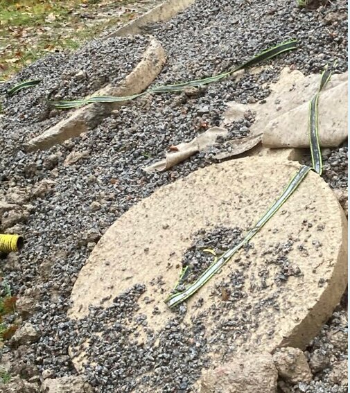 Betongplattor med gröna band och grus runt omkring, potentiellt felaktig förankring enligt installationsanvisning.