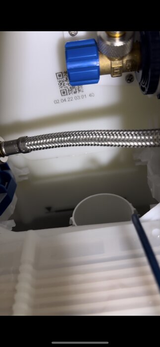 Anslutning och ventil i innerdelen av vägghängd toalett, Grohe, med blå komponent, ursprung för vattenläckage.