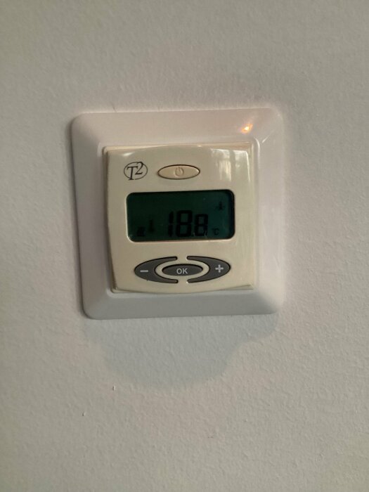 Termostat för golvvärme, äldre modell med display som visar 18,8 grader Celsius.