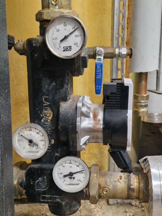 Tre termometrar på en panninstallation med Laddomat-system, visar temperaturer runt 70–80 grader. Diskussion om korrekt pump- och ventilfunktion.