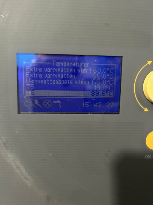 Skärm på ett värmesystem som visar temperaturinställningar för varmvatten, med olika start- och stopptemperaturer, samt aktuell tidsangivelse.
