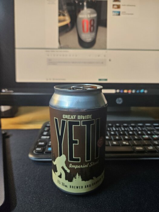 Burk med Great Divide Yeti Imperial Stout framför en datorskärm som visar en ölbild.