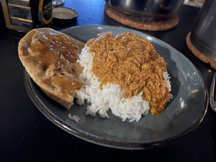 Tallrik med ris, butterchicken, naanbröd och mango chutney.