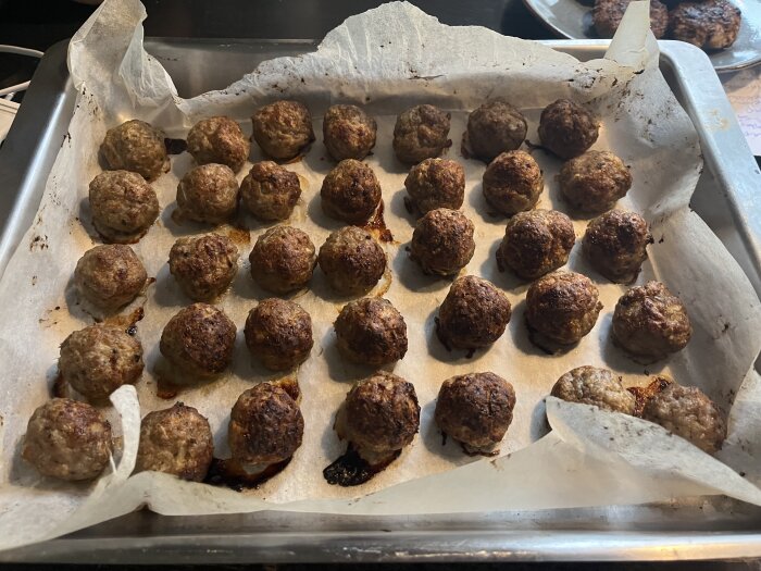 Köttbullar på ugnsplåt med bakplåtspapper, klara efter tillagning i ugnen.