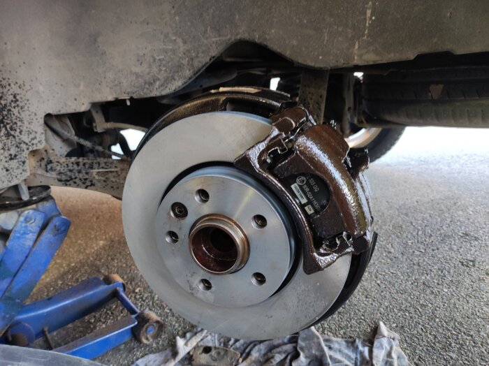 Bilbroms med nyinstallerad bromsskiva och bromsok under bilen, färdigt arbete.