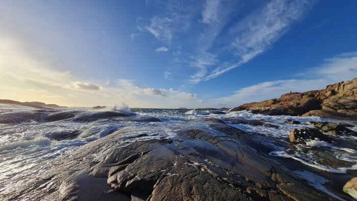 Vy över Tjurpannan i Bohuslän med vågor som slår mot klipporna under en klarblå himmel.