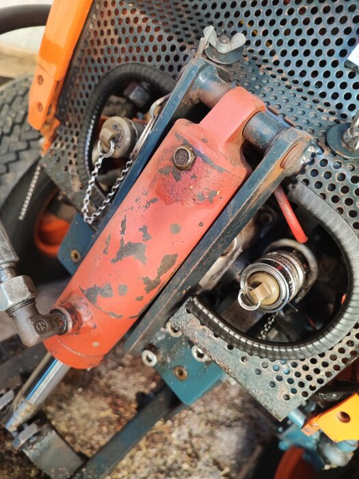 Hydraulisk snabbkoppling på en traktor med orange detaljer och slangkopplingar.