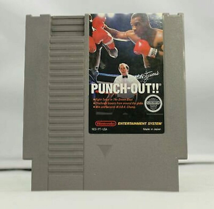 Nintendo-spelkassett med omslaget för "Mike Tyson's Punch-Out!!", visar boxare i ringen och en domare.