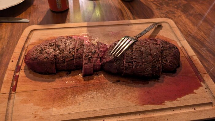 Grillad mufflonstek, skivad och serverad på en skärbräda med en gaffel.