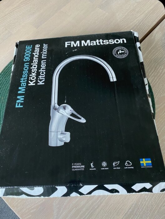 Kartong med FM Mattsson 9000E köksblandare avbildad på framsidan, text på svenska och engelska samt olika symboler och svensk flagga.