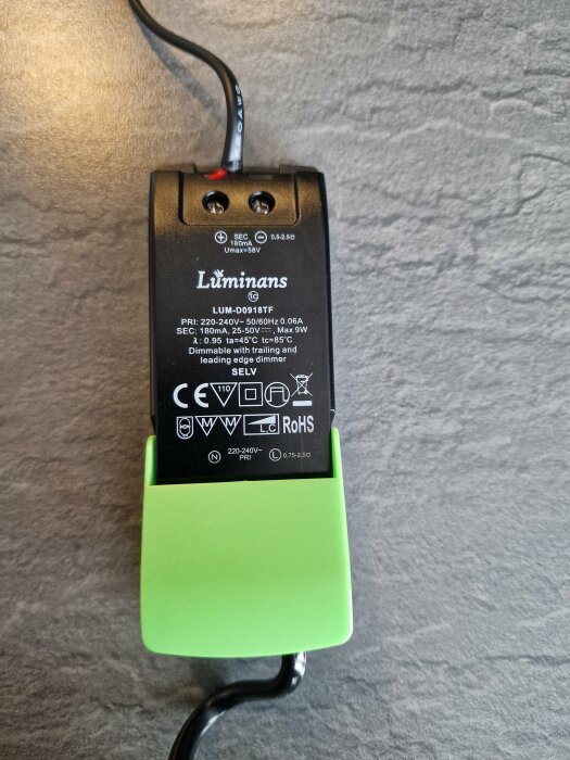 Svart och grön LED-drivdon med märkningen "Luminans LUM-D0918TF", uppvisar elektriska specifikationer och certifieringar på baksidan.