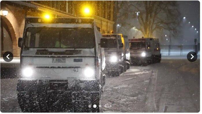 Bandvagnar kör genom snöigt landskap med blinkande varningsljus i mörkret.