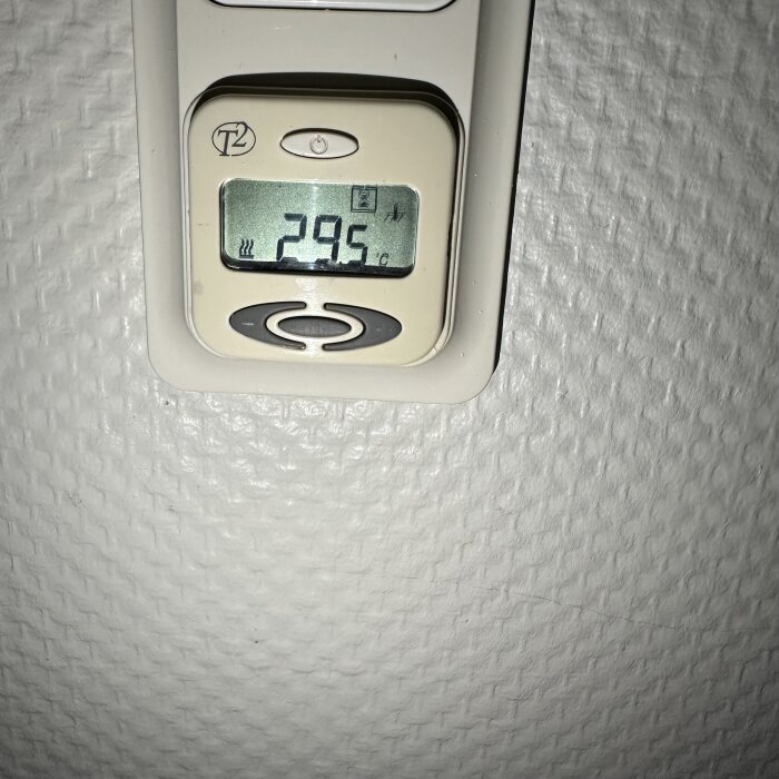 Termostat på vägg visar 29,5 grader med en symbol för värmekabel till vänster om siffrorna.