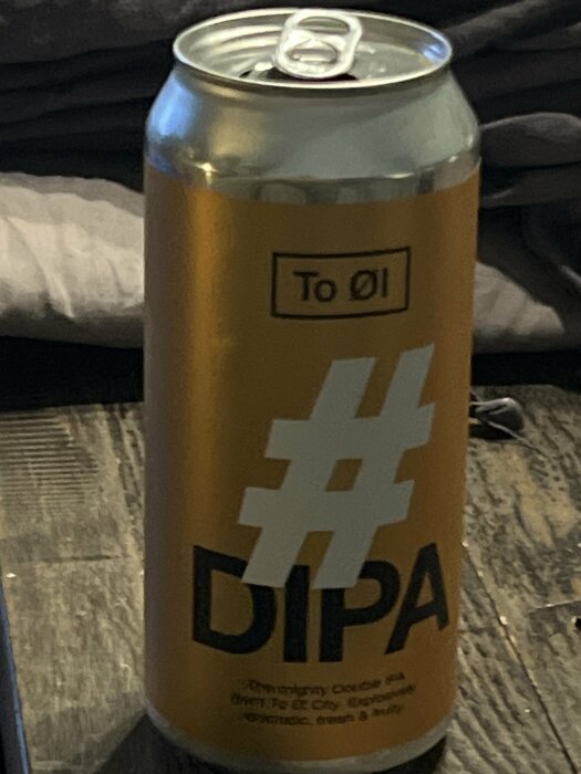 En burk dansk öl av märket To Øl med etiketten "#DIPA" står på ett bord.