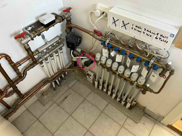 Blandningsventil och rörkopplingar i ett värmesystem med markerad Siemens komponent, omgiven av flera termostater och rör i ett teknikrum.