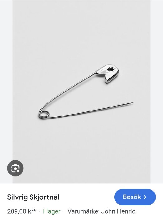 Silvrig skjortnål på vit bakgrund, prissatt till 200 kr.